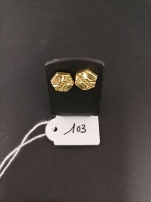 a close up of a pair of gold earrings on a black surface