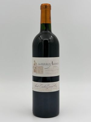 a bottle of red wine sitting on top of a white table