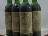 four bottles of wine are lined up on a glass shelf