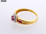 a close up of a gold ring with a ruby and diamond