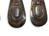 three silver spoons with a monogram on them sitting next to each other