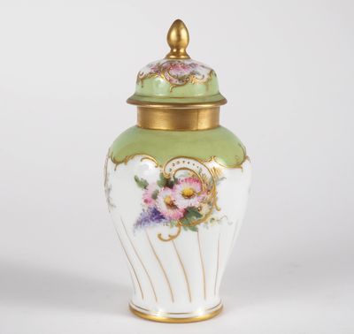 a close up of a green and white vase with flowers on it