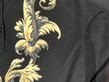 a close up of a black shirt with a gold floral design on it