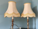 une paire de lampes de table en laiton avec des abat-jours à franges, posées sur une table noire