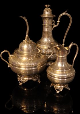 three pieces of silverware on a black surface with a black background