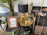 a table with plants and a lamp on it in the corner of a room