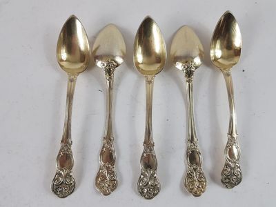 four spoons are lined up in a row on a white surface