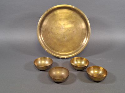 three brass bowls and a tray on a gray surface