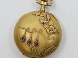 a close up of a gold pocket watch on a white surface