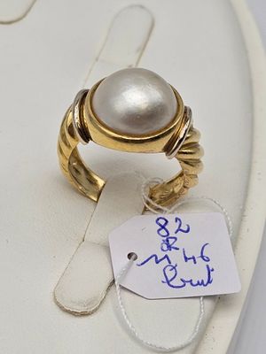 une bague ornée d'une perle et à laquelle est attachée une étiquette de prix
