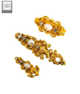 un gros plan sur une paire de broches en or et perles
