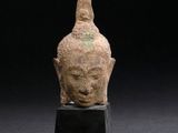 an ancient bronze head of a buddha on a black stand