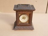 a small clock sitting on a table with a box in the background