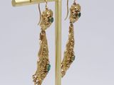 pair of gold and emerald earrings on a gold plated stand