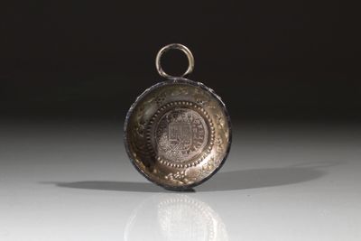 une montre de poche en argent posée sur une table, sur fond noir