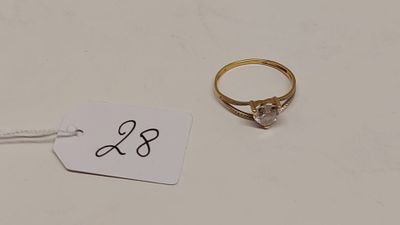 une bague en or sertie d'un diamant, à côté d'une étiquette de prix