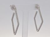 une paire de boucles d'oreilles en diamant posée sur un présentoir, sur fond blanc