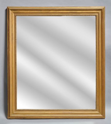 un miroir à cadre doré posé contre un mur gris