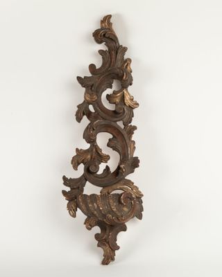 an ornately carved wooden wall hanging on a white wall