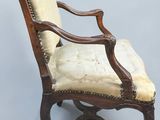 an old wooden chair with a beige upholstered seat
