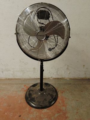 un ventilateur posé sur un support dans une pièce