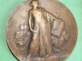 une médaille de bronze sur laquelle figurent une femme et un chien