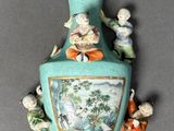 a blue vase with figurines on it on a table