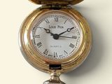 a gold pocket watch with a key hanging from it ' s side