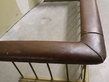 a brown leather bench in the middle of a room