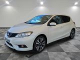 une Nissan Versa blanche garée sur un sol en dalles à damier