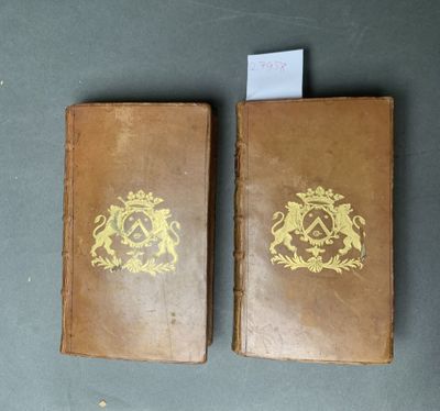 deux vieux livres ornés de dorures, posés sur une table