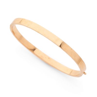 un bracelet rigide en or jaune sur fond blanc