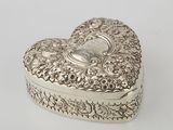 a silver heart shaped box on a white surface