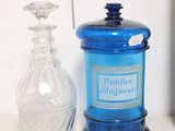 un bocal en verre bleu posé sur une étagère à côté d'une horloge