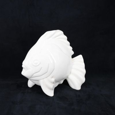 une figurine de poisson blanc posée sur une surface noire