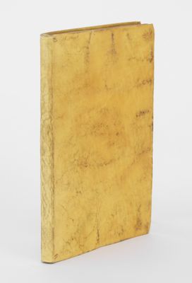 un vieux livre à la couverture jaune posé sur une surface blanche