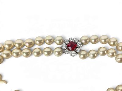 a pearl necklace with a red stone surrounded by pearls