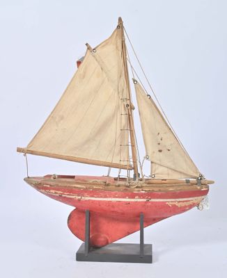 wooden model of a sailboat with a red hull and white sails