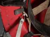 a close up of a red suitcase with a brown strap