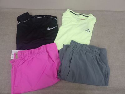 trois paires de shorts Nike et un t-shirt posés sur un canapé