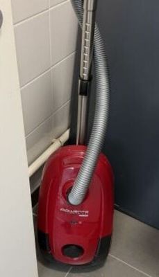 un aspirateur rouge dans un coin de la salle de bains