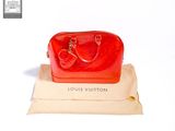 a red bag sitting on top of a bag on top of a pillow