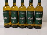 four bottles of white wine are lined up on a table