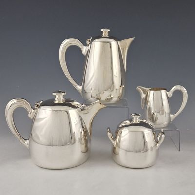 three pieces of silver tea and coffee set on a table