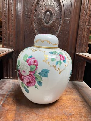 un vase blanc orné de fleurs roses, posé sur une table