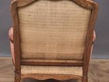 an old wooden chair with a pink upholstered seat on a parquet floor