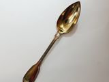 a silver spoon with a gold handle on a white surface