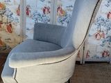 an upholstered chair in front of a wall with floral wallpaper