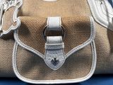 a white purse with a silver handle on a blue surface