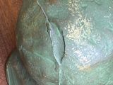 a green sculpture of a man ' s head on a wooden floor
